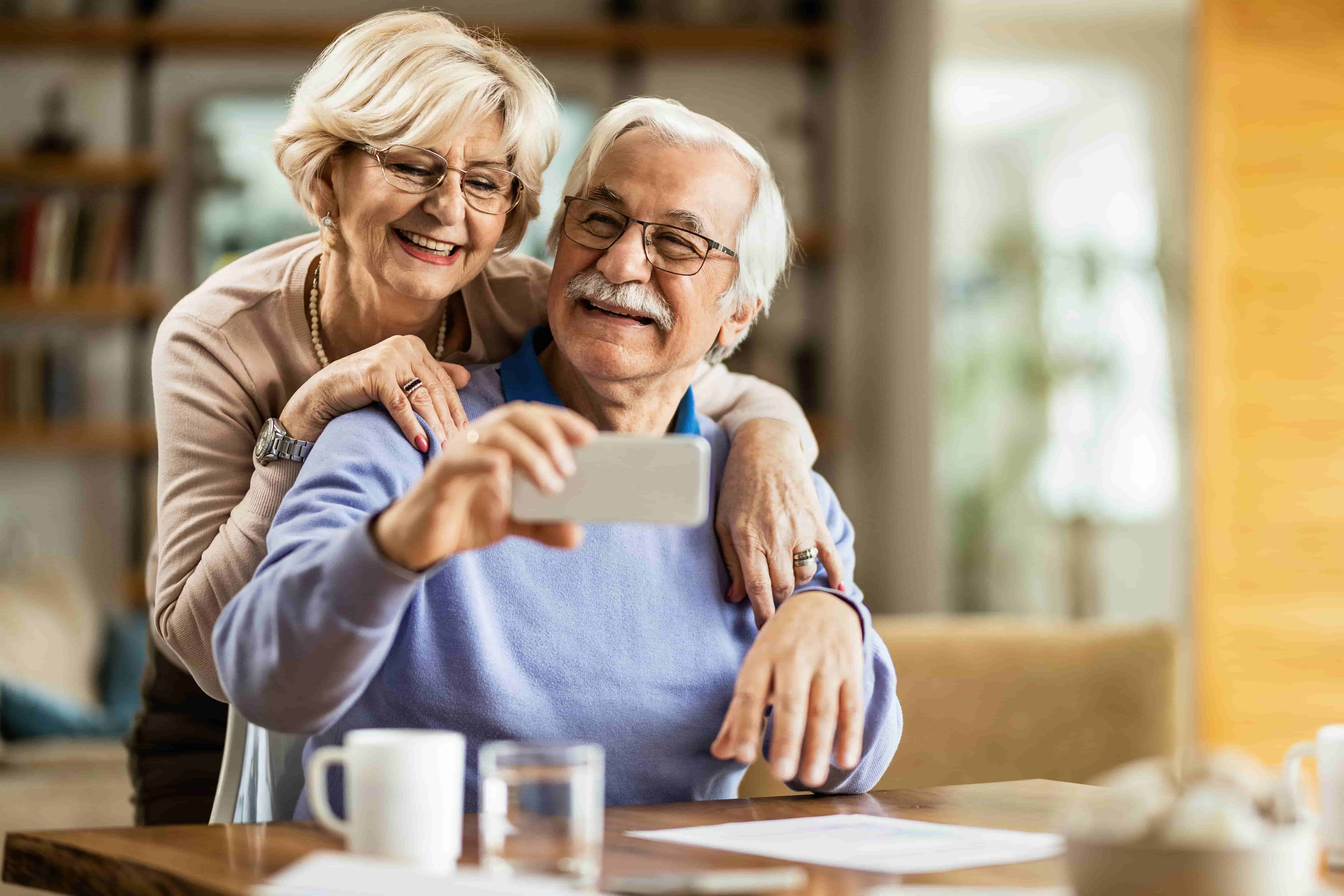 happy mature couple using mobile phone having fun while taking selfie