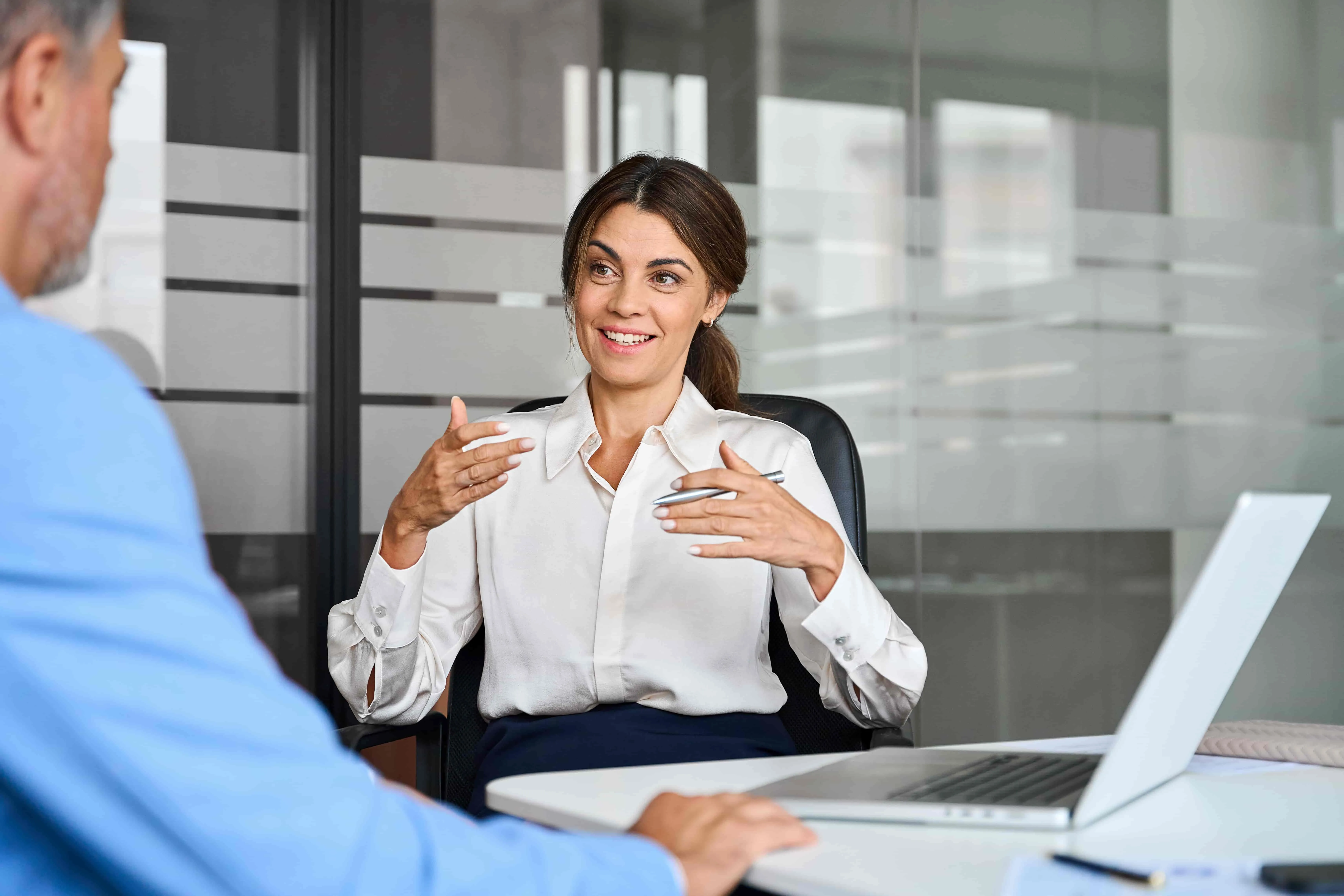 Female executive speaking to colleague working at office corporate meeting.